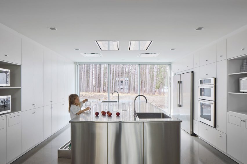 A kid in a kitchen with a metal island