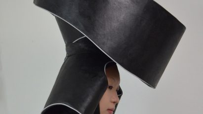 A photograph of a person wearing a large headpiece which is designed to collect rainwater