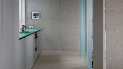 View into a plain kitchen with a concrete wall at the far end