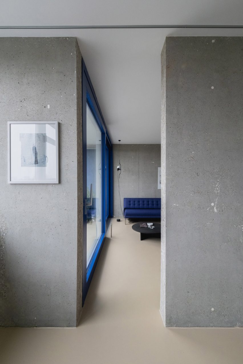 View into living area with blue sofa and blue window frame