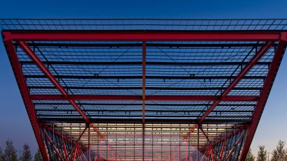 Front few of cantilevered red trusses and glass structure