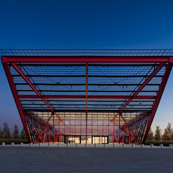 Front few of cantilevered red trusses and glass structure