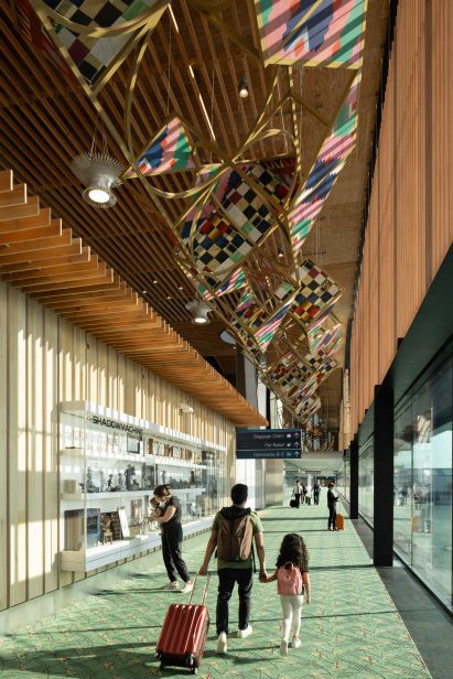 Child and father walking under art at Portland new airport terminal