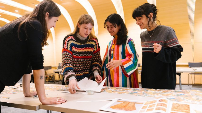 Photograph of four students gathered around a table looking at work.