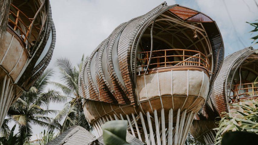 Photograph of a curvaceous architectural structure set in a tropical environment.