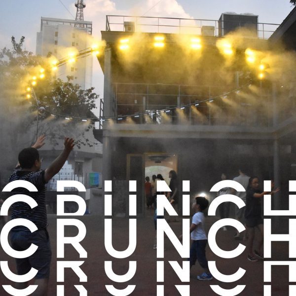 A photograph of a building masked by smoke, with yellow lights shining from it. There is distorted white text over the image that reads 'crunch'.