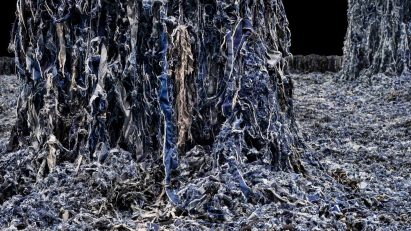 A close up photograph of a large floor covered in blue denim scraps, with two columns emerging from it, also covered.