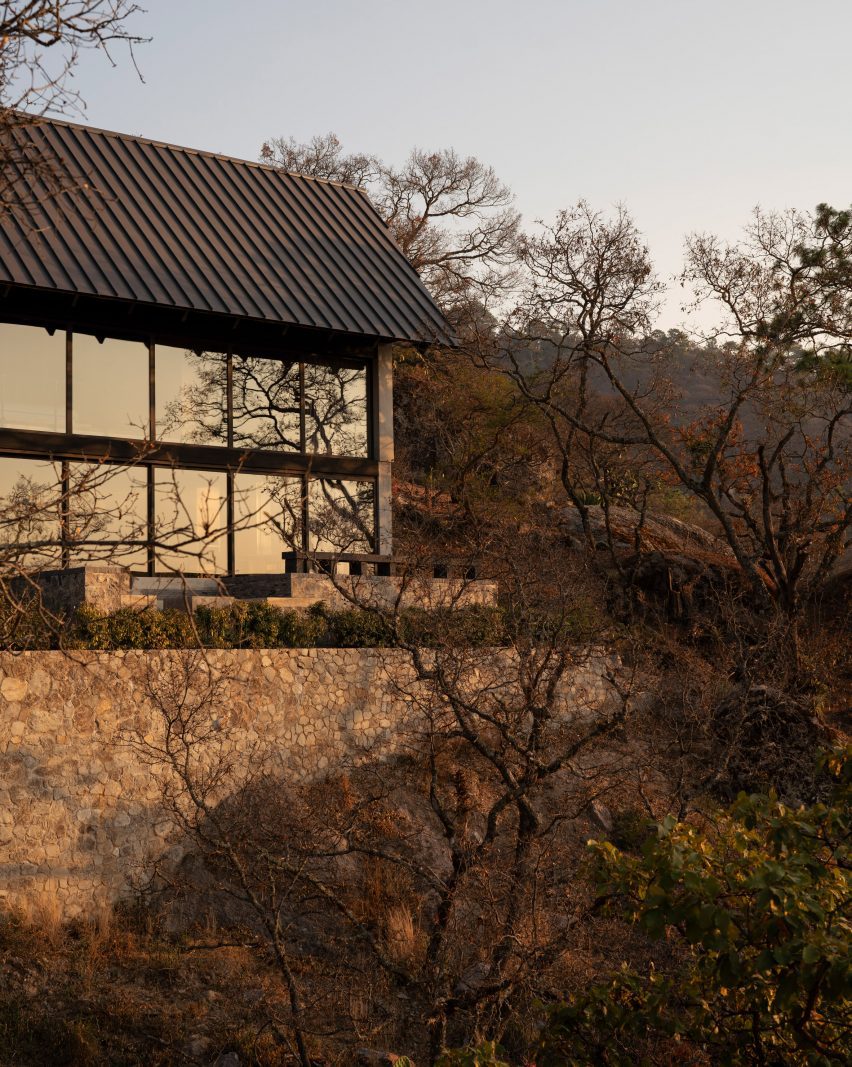House with glass facade on top of stone wall
