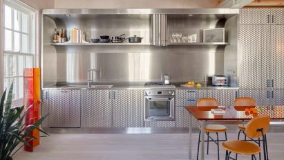 Brushed stainless steel kitchen with orange chairs