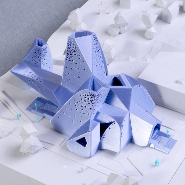 A photograph of an architectural model of a chapel in tones of blue atop a white surface.
