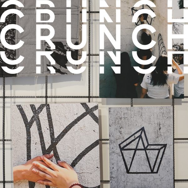 A photograph of a series of images displayed on a wall in tones of grey and black, with a person's hand touching one of them. There is distorted white text over the image that reads the word 'crunch'.