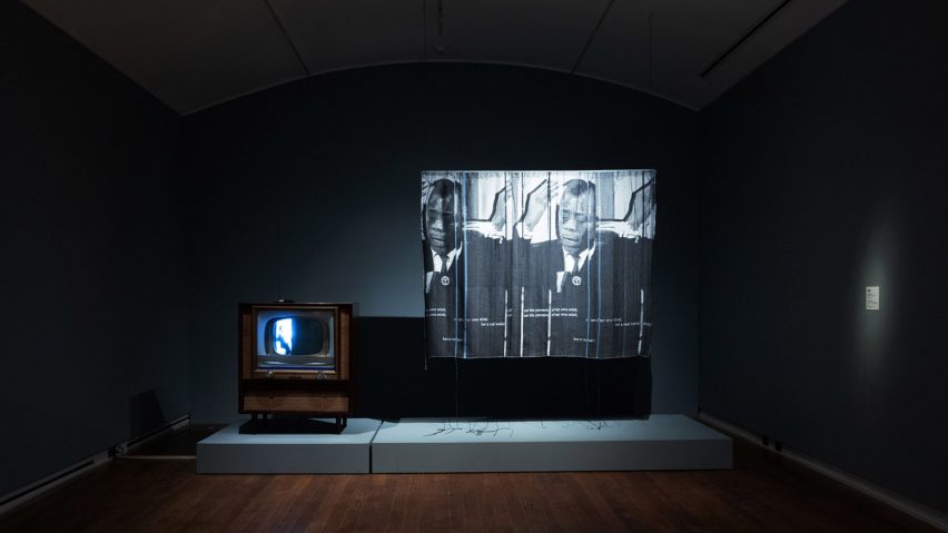 Photograph of an exhibition showing a dark room with art projected on to a screen.
