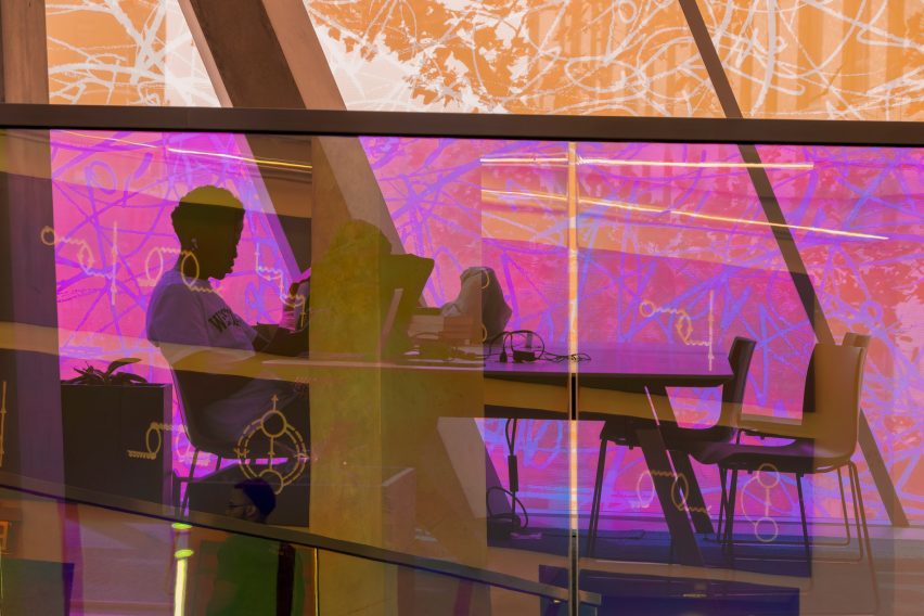 Woman sitting in front of pink panels