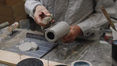 Person smoothing grey material onto exterior of lamp base