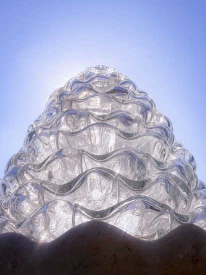 Worm's-eye view photo of the Serpentine Bell sculpture by AAU Anastas lit from behind by the sun