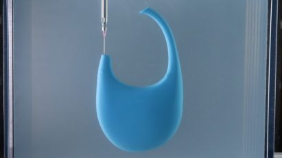 A photograph of a blue Coperni bag being rapid liquid 3D-printed