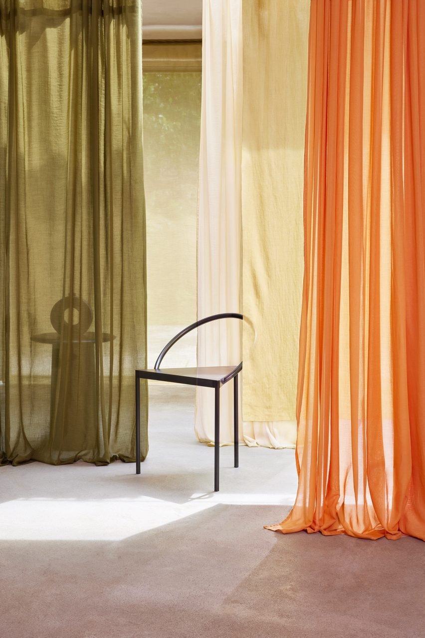Photo of Kikrby Design's Aloe fabric hanging in long curtains in a room in an olive green, light cream and bright orange colour