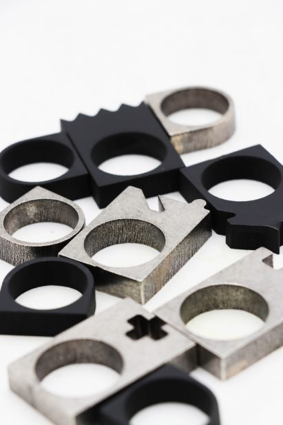 Close-up photo of silver and black chess piece themed chunky rings scattered on a surface