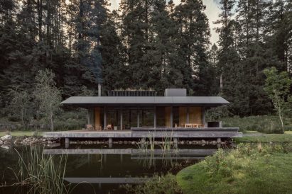 Steel house by lake with concrete foundation visible