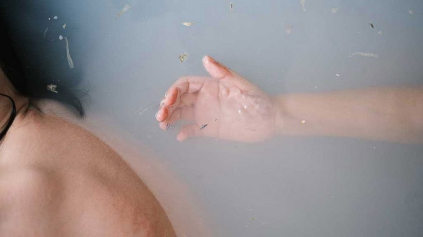A photograph of a person submerged in water. There is a hand behind them, reaching towards them.