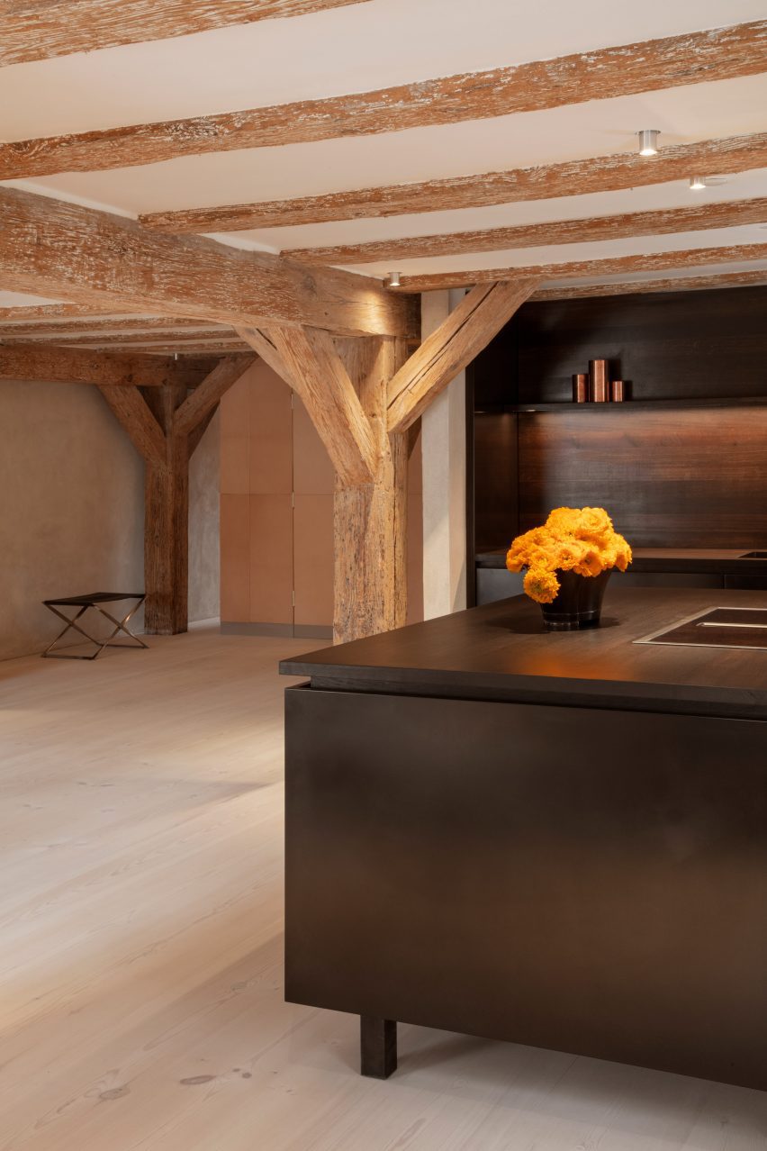 Black kitchen island and fittings topped with orange flowers