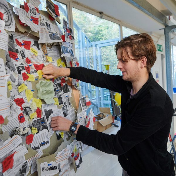 A photograph of a person in black clothing handling a display in on a noticeboard.