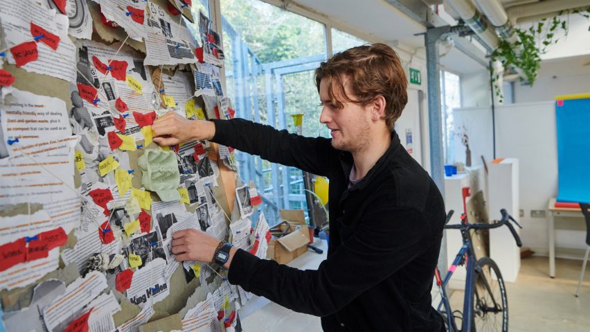 A photograph of a person in black clothing handling a display in on a noticeboard.
