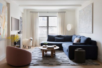 Light-filled living space with a navy sectional and pink occasional chair