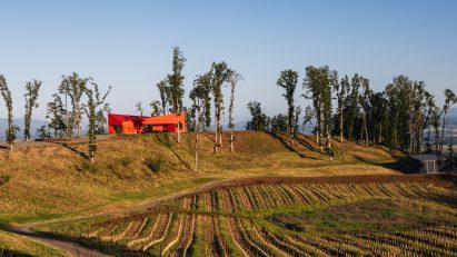 Red building on hill above winery