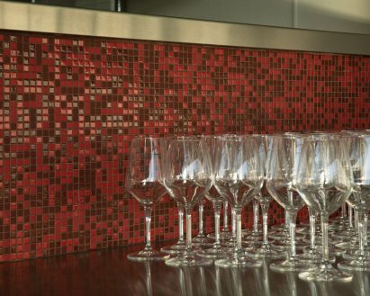 Tiny red and burgundy tiles behind rows of wine glasses