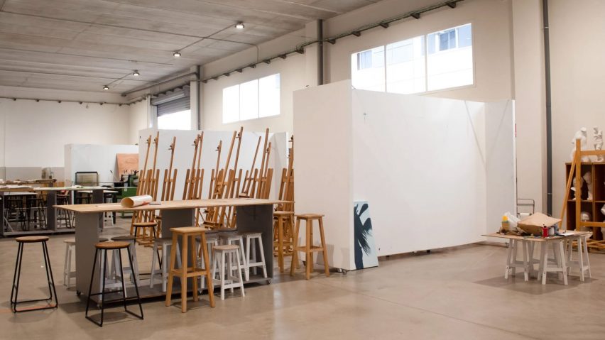 A photograph of a room with chairs and wooden easels in it.