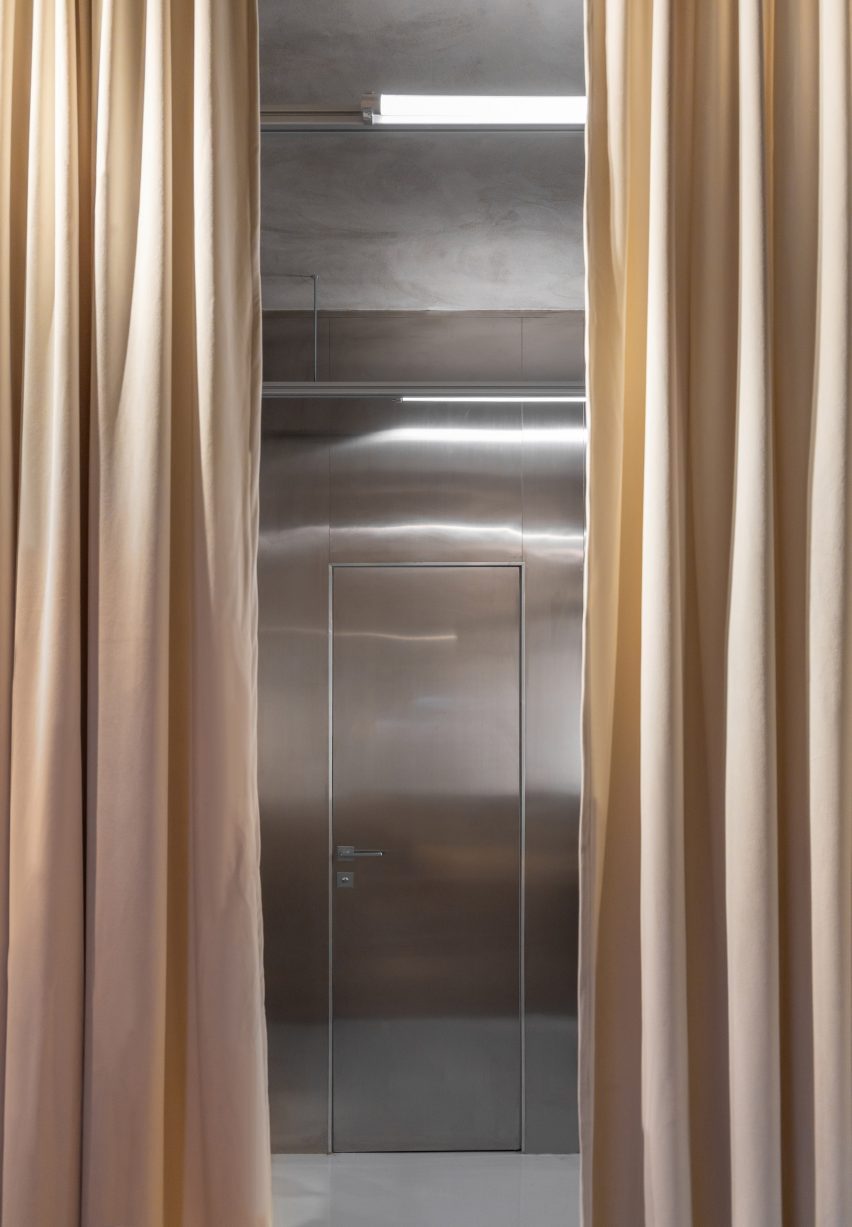 Beige drapes open before stainless steel door