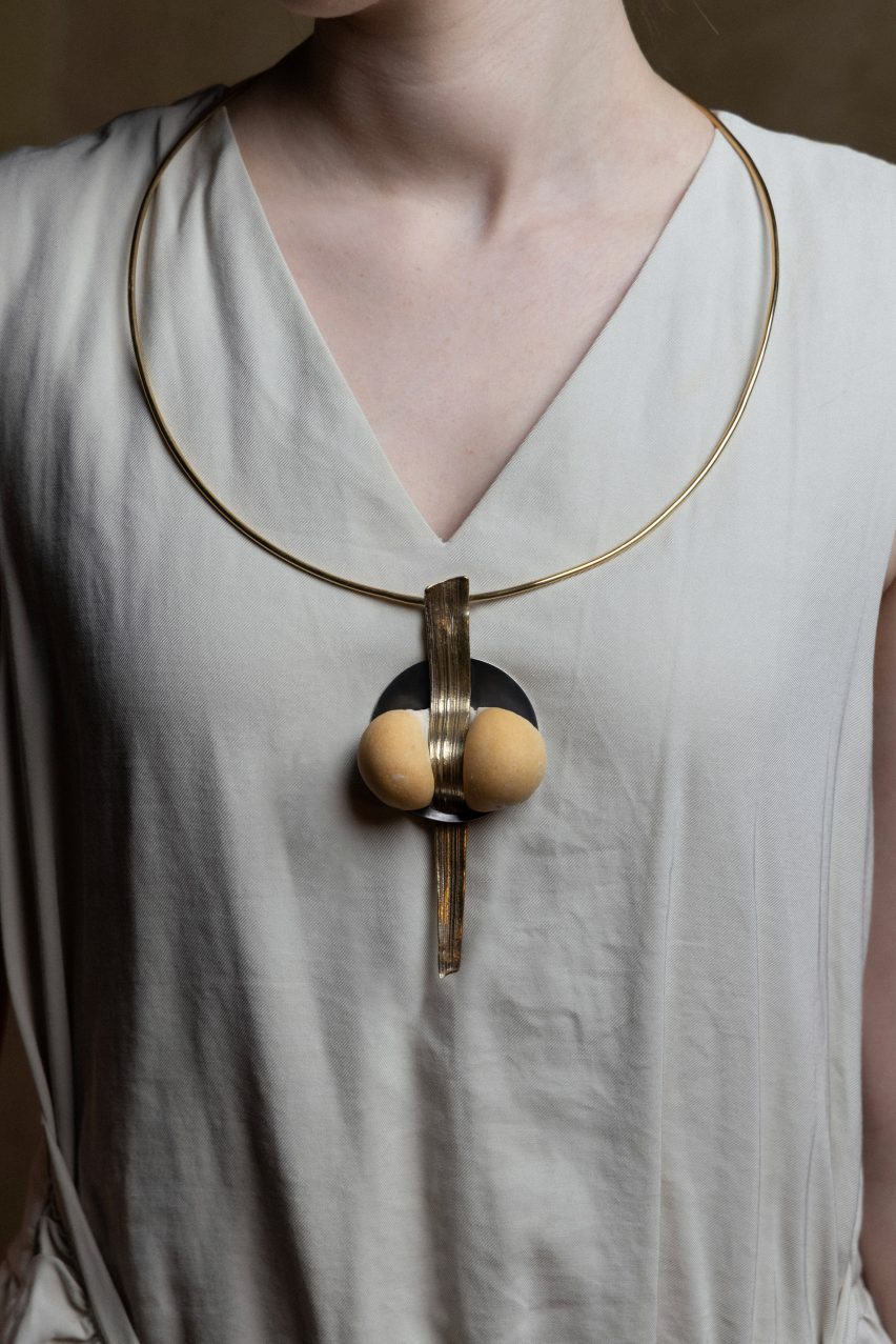 Photo of a woman's torso with a chunky pendant formed from a ball of baked dough pressed through the centre by a long, textured metal element