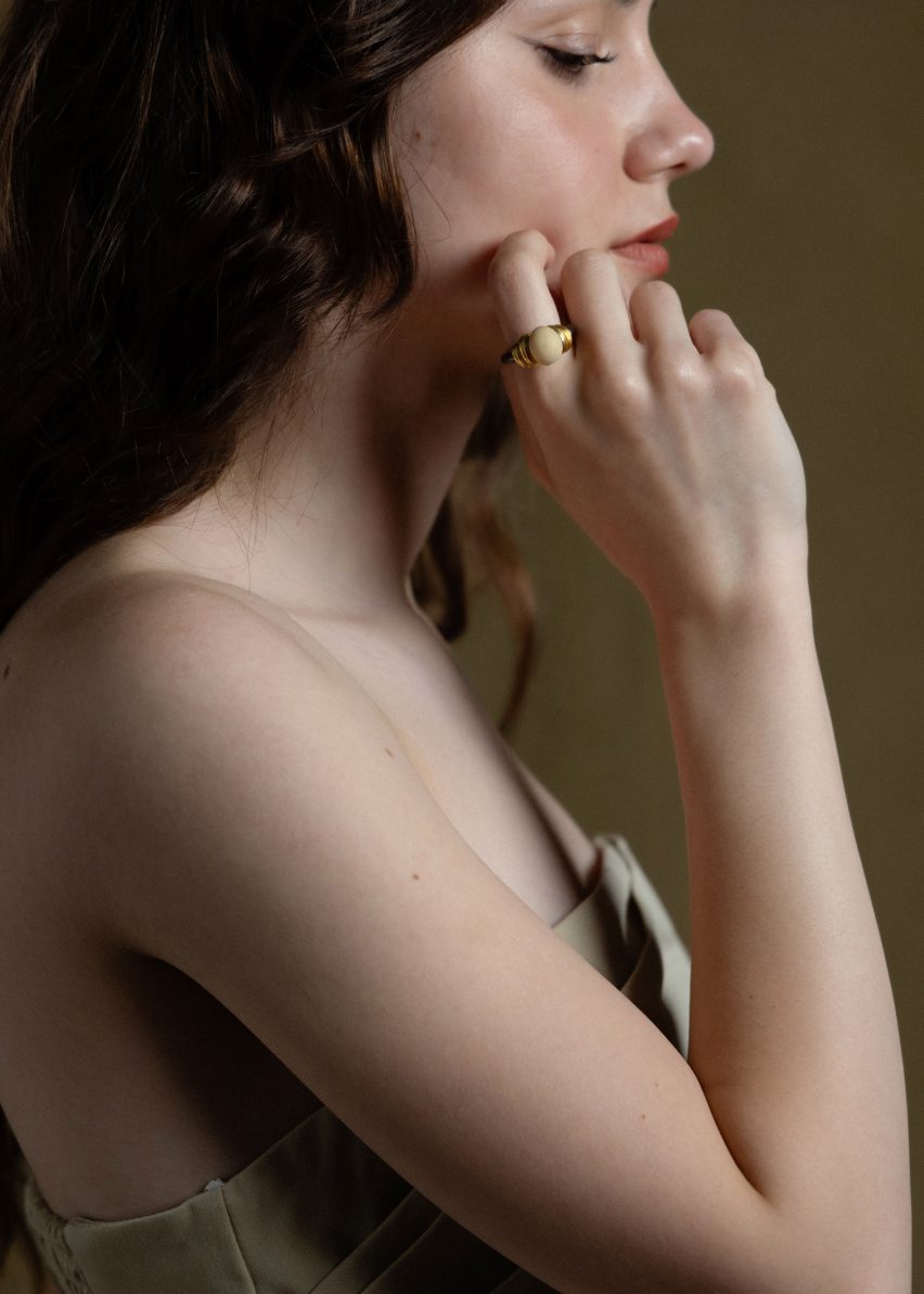 Profile photo of a woman raising one hand to her cheek. A silver ring with a small bread dough centrepiece is on her pointer finger