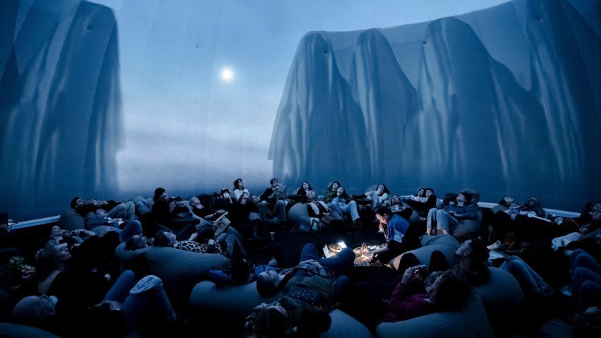 people in front of a projected image onto a screen of a cliff