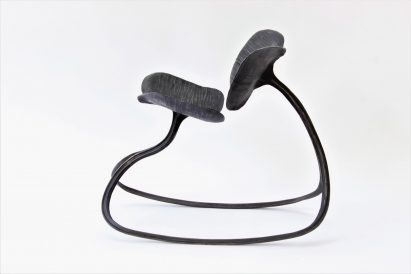 A photograph of a rocking chair in tones of black against a white backdrop.
