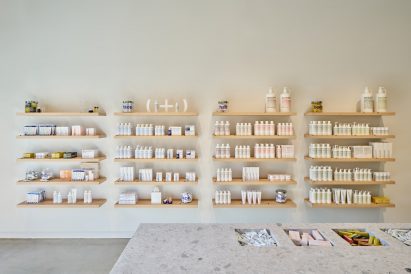 Malin+Goetz products displayed against a blank wall on white oak shelves