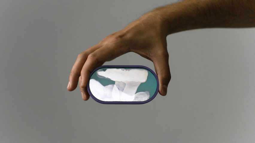 A photograph of a person's hand holding an oval-shaped object in tones of blue and white.