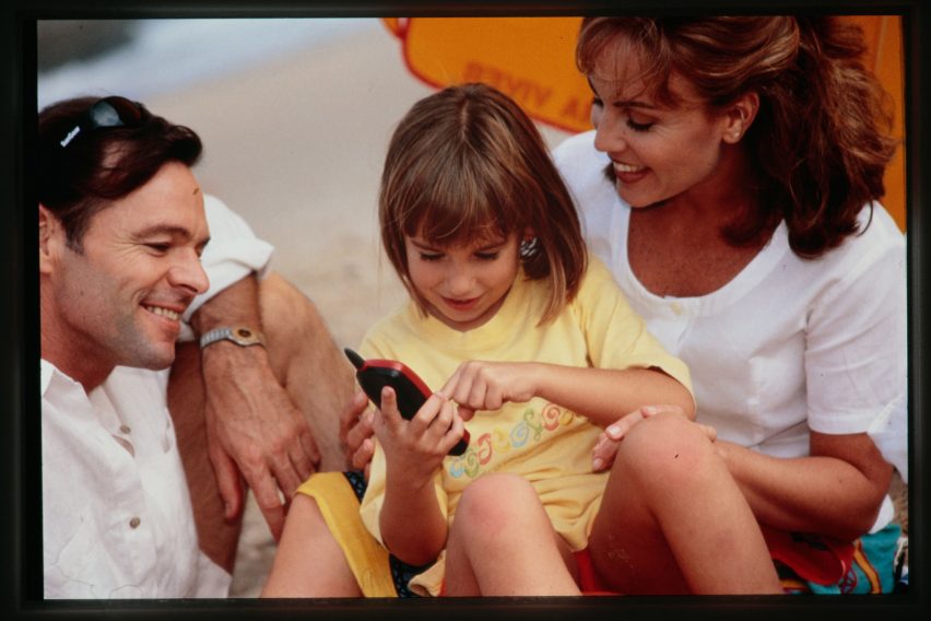 Promotional photo from the 1990s of a man and woman holding a girl using a phone