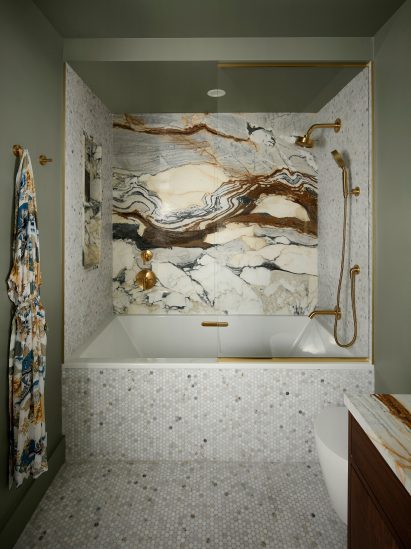 Bathroom featuring dramatically veined marble, penny tiles and brass fixtures