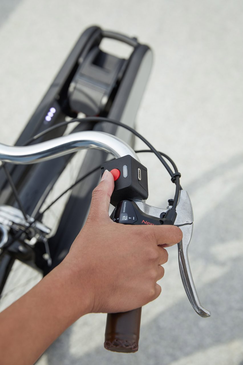 Person pressing down red button on e-bike