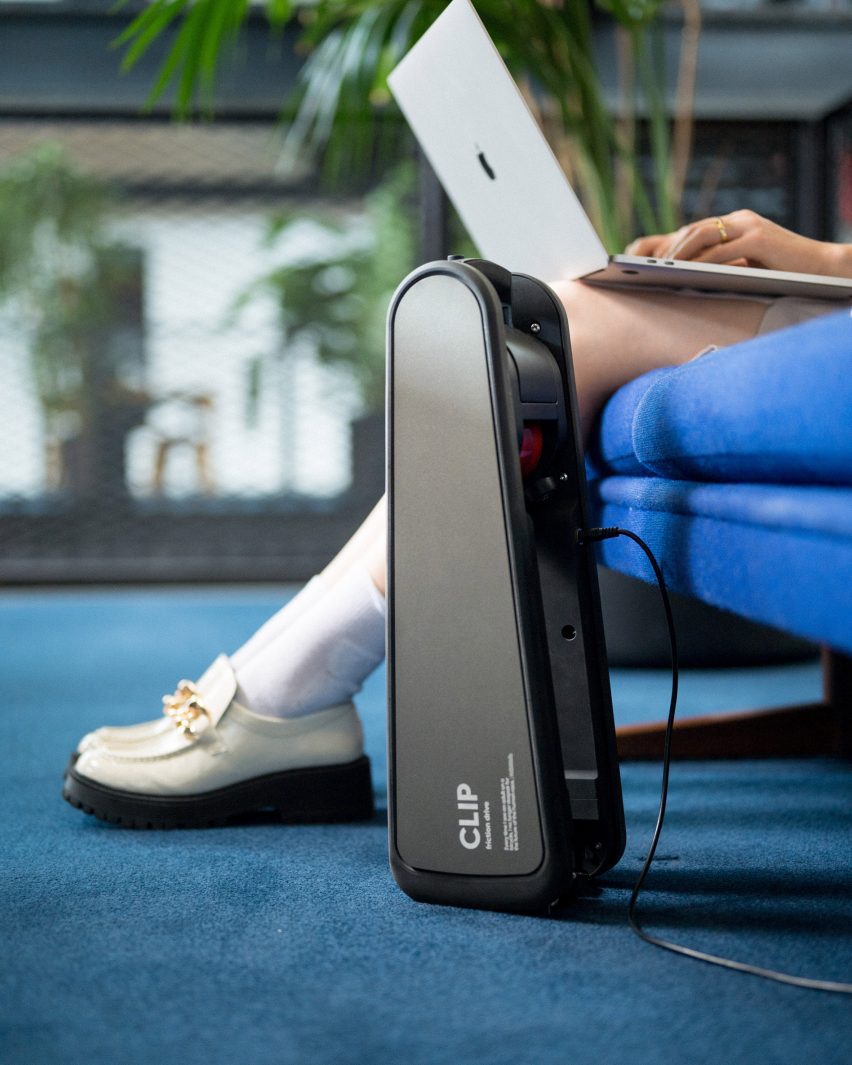 E-bike device charging on the floor with person working on laptop