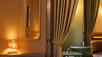 A photograph of an interior with large green curtains and warm yellow lighting.