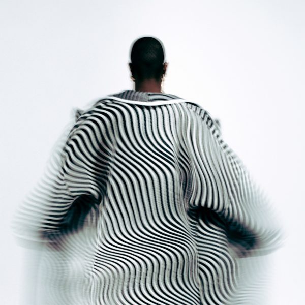 A photograph of a person from behind wearing a black and white patterned garment which is in motion.