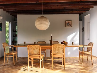 Dining room with large table, six chairs, and paper pendant light above