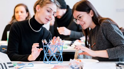 Two students discussing their design project with an architectural model in front of them