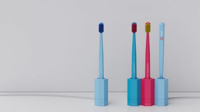 A photograph of four toothbrushes in hexagonal holders, in tones of blue and pink.