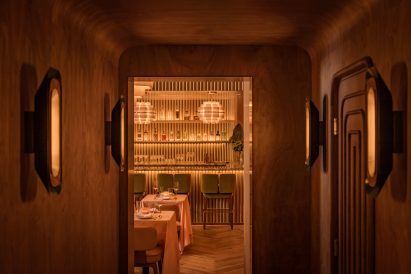 A corridor enveloped in walnut panels that curve onto the ceiling