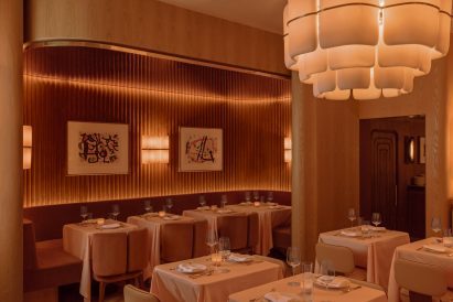 Restaurant interior bathed in soft, warm light from sconces, pendants and cove lighting