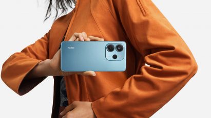 Person holding smartphone in front of light grey background 